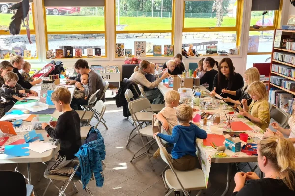 To langbord med vaksne og barn sittande på stolar rundt.