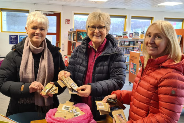 tre damer i eit biblioteksmiljø