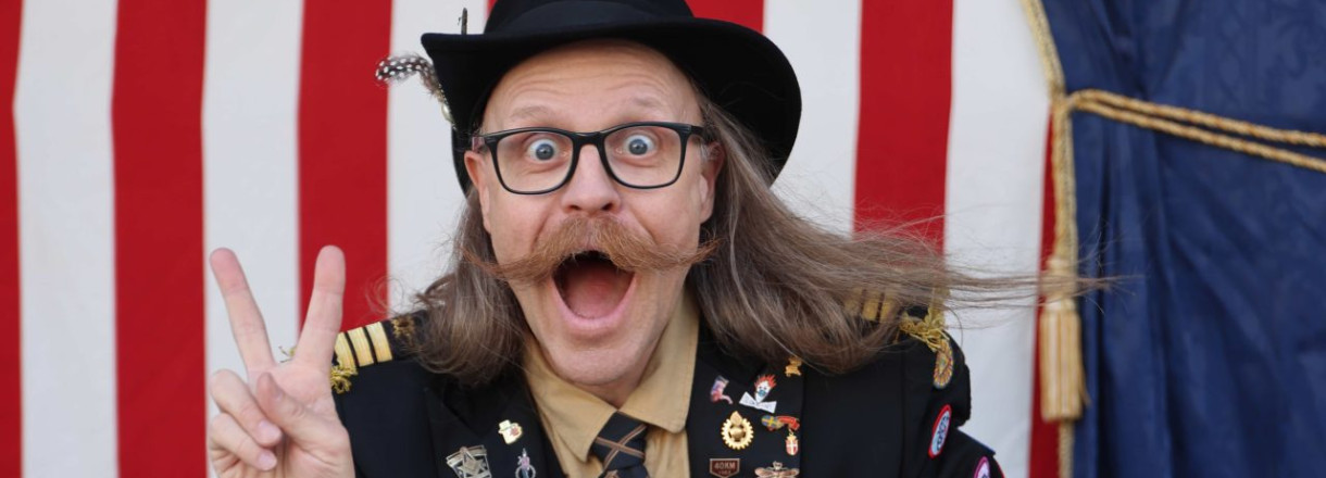 Ein mann med hatt, briller og stor bart