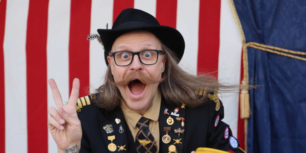Ein mann med hatt, briller og stor bart